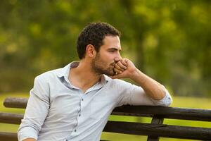 Deprimido empresario es sentado a el parque y pensando acerca de alguna cosa foto