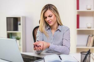Businesswoman having wrist pain while working in her office photo