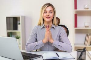 Businesswoman meditating in her office while working photo