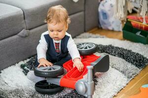 linda pequeño bebé chico jugando y reparando su primero bicicleta foto