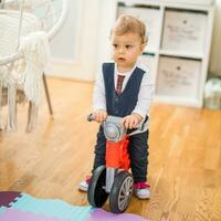 Image of cute little baby boy riding his first bike photo