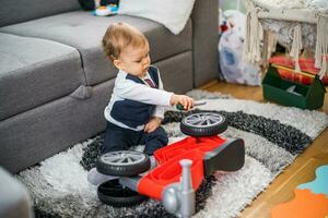 linda pequeño bebé chico jugando y reparando su primero bicicleta foto