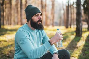 Tired man resting after exercise and drinking water in the nature photo