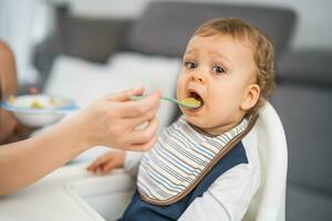 Cute baby boy eating while sitting in a high chair photo