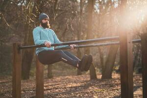 hombre disfruta ejercicio empujar UPS en paralelo barras en el parque. foto