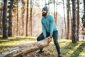 Strong sporty man is lifting tree stump photo