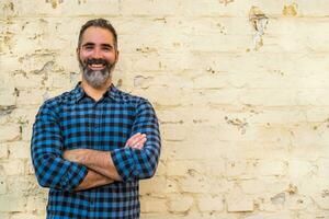 Portrait of modern businessman with beard standing in front of brick wall outdoor photo