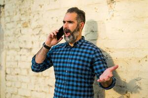 Businessman with a beard having conflict while talking with someone on the phone photo