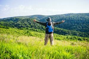 Man hiker with arms raised enjoys in beautiful view in the nature photo