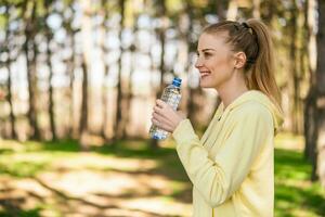 Sporty woman drinking water in the nature photo