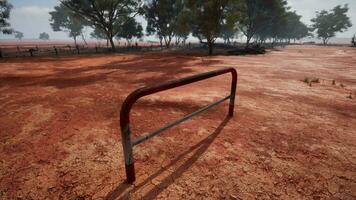 A rustic red dirt field with a charming fence and trees in the background video