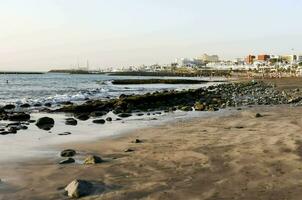 a beach with rocks and sand in front of the ocean photo