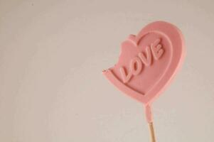 a pink heart shaped lollipop with a bite out of it photo