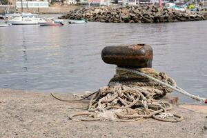 a rope tied to a metal object on the shore photo