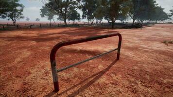 A rustic red dirt field with a charming fence and trees in the background video