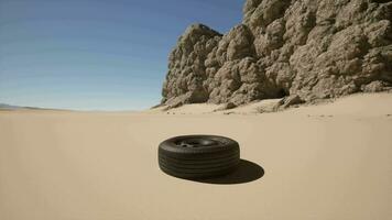 A tire laying on the sand in front of a rock formation video