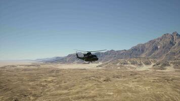 A helicopter flying over a desert landscape with mountains in the background video