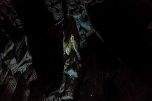 the cave is dark and has a large rock formation photo