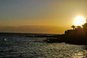 the sun is setting over the ocean and the shoreline photo