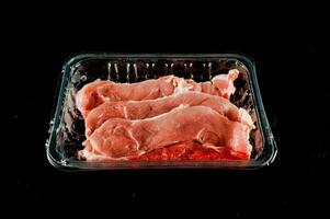 raw meat in a plastic container on a black background photo