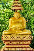 a golden buddha statue sitting on top of a wooden base photo