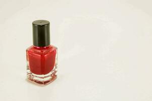 a bottle of red nail polish on a white surface photo