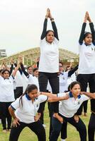 nuevo Delhi, India, junio 21, 2023 - grupo yoga ejercicio sesión para personas a yamuna Deportes complejo en Delhi en internacional yoga día, grande grupo de adultos asistiendo yoga clase en Grillo estadio foto