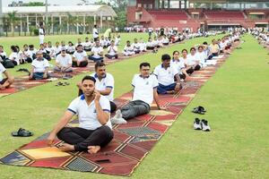 nuevo Delhi, India, junio 21, 2023 - grupo yoga ejercicio sesión para personas a yamuna Deportes complejo en Delhi en internacional yoga día, grande grupo de adultos asistiendo yoga clase en Grillo estadio foto