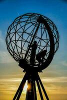 the sun sets behind the globe sculpture photo