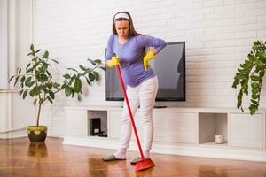 Tired pregnant woman having pain in back while she is  cleaning her house. photo