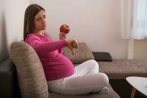 Sad pregnant woman doesn't want to eat fruit. photo