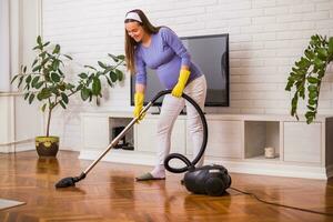 hermosa embarazada mujer disfruta limpieza su casa. foto