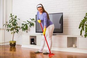 Beautiful pregnant woman enjoys cleaning her house. photo