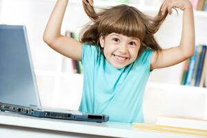 Cute little girl having fun and using laptop photo