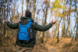 Man hiker with arms raised enjoys in beautiful view in the nature photo