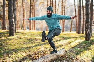 Sporty man walking on tree stump during exercising in nature photo