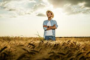 Happy farmer is standing in his growing barley field photo