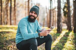 Man using phone and drinking water after exercise in the nature photo