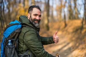 caminante demostración pulgar arriba mientras excursionismo en naturaleza foto