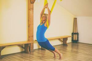 Woman doing aerial yoga in the fitness studio photo