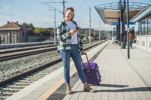 Happy woman using mobile phone on a train station photo