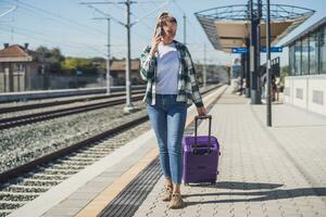 contento mujer utilizando móvil teléfono en un tren estación foto