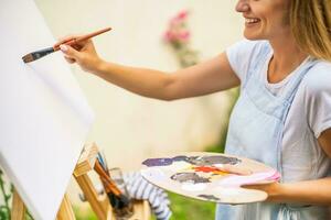 Woman enjoys woman painting on canvas outdoor photo