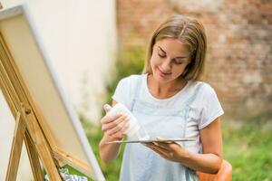 Woman enjoys woman painting on canvas outdoor photo