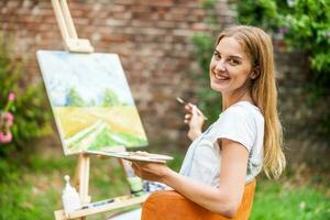 Woman enjoys woman painting on canvas outdoor photo