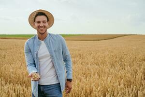 Happy farmer is standing in his growing wheat field photo