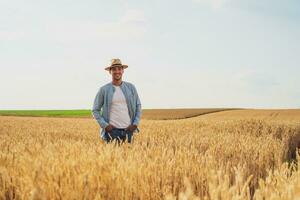 Happy farmer is standing in his growing wheat field photo