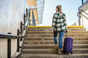 Woman with suitcase and ticket going up by stairs in the train station photo