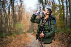 Image of man drinking water while hiking photo