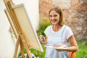 Woman enjoys woman painting on canvas outdoor photo